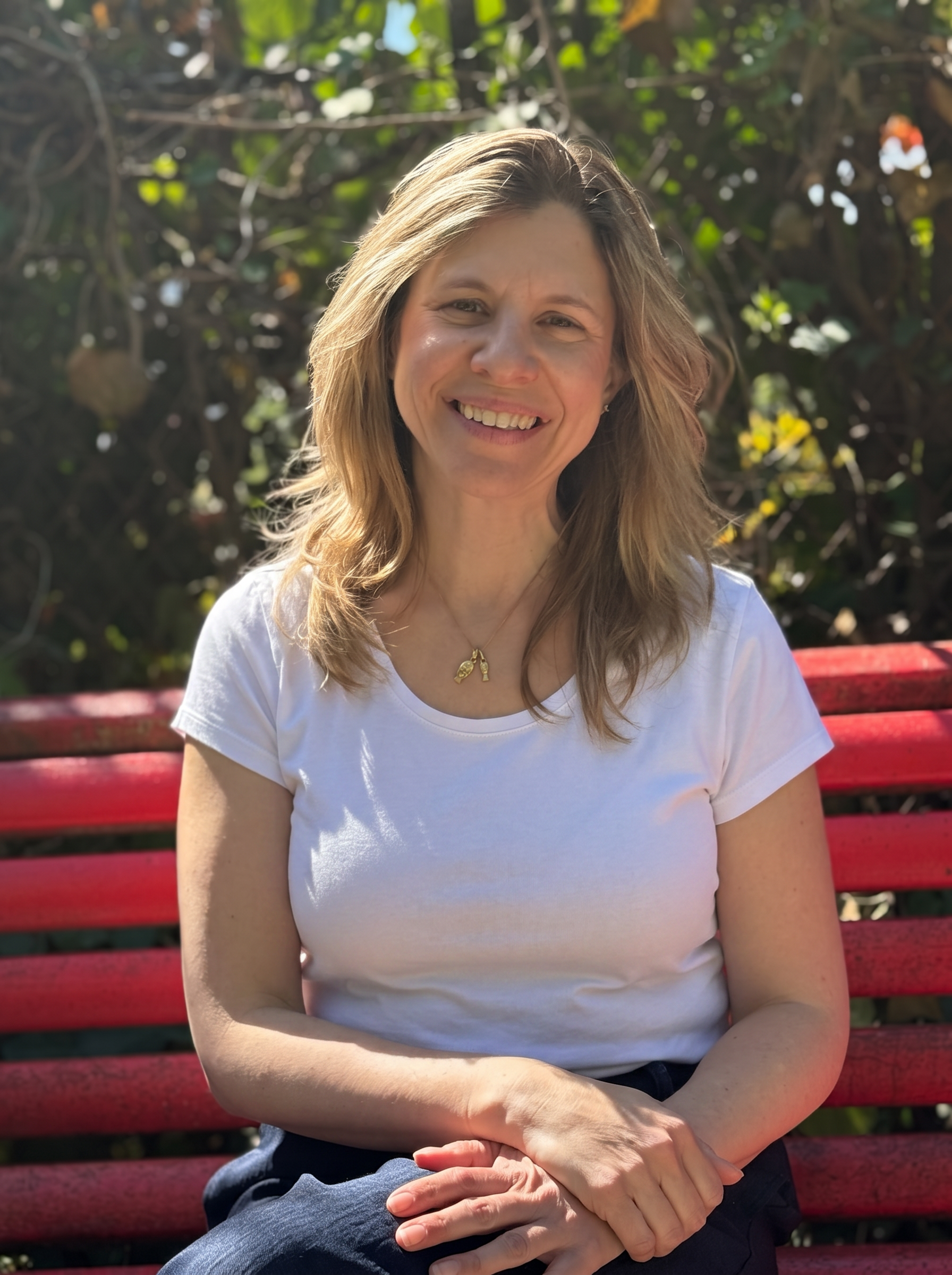 Mary sitting outdoors on a garden bench in a white shirt