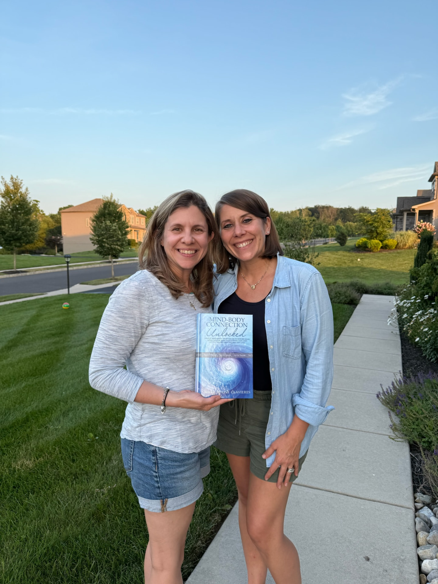 Mary and a friend outdoors holding the book